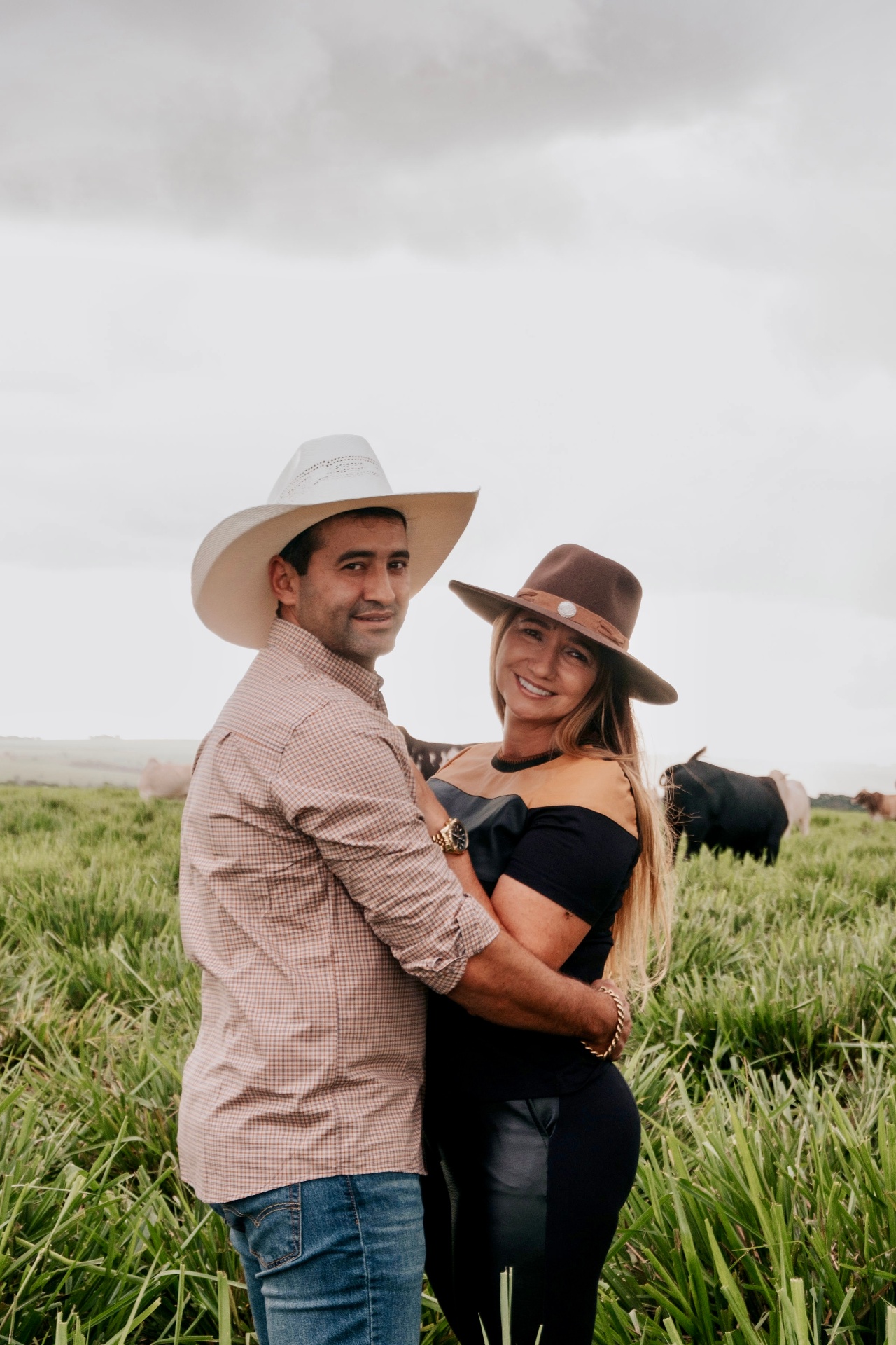 Anderson e Dinair, Casal da Pecuária, em meio ao pasto com gado ao fundo